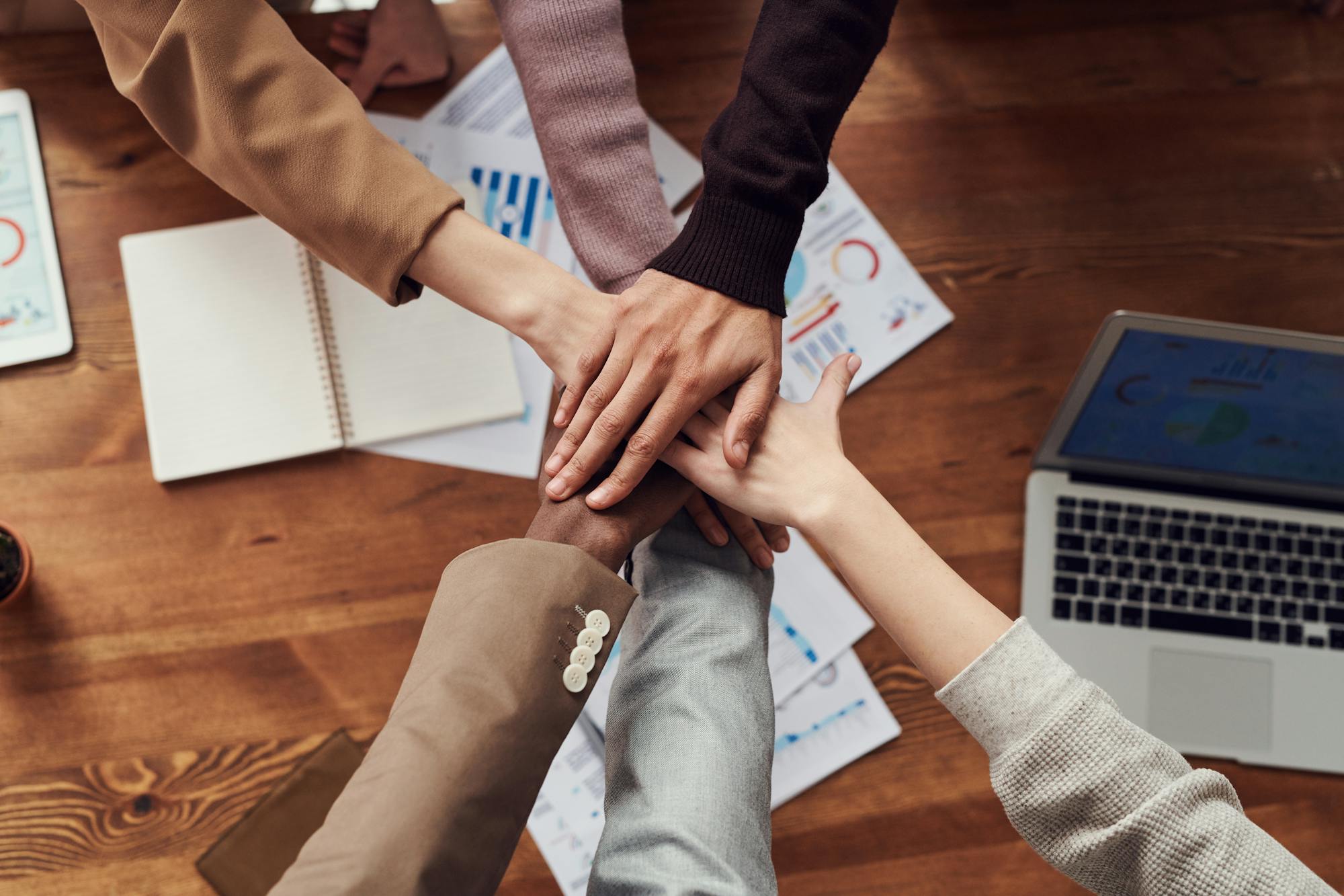 Equipo profesional uniendo manos sobre una mesa de trabajo